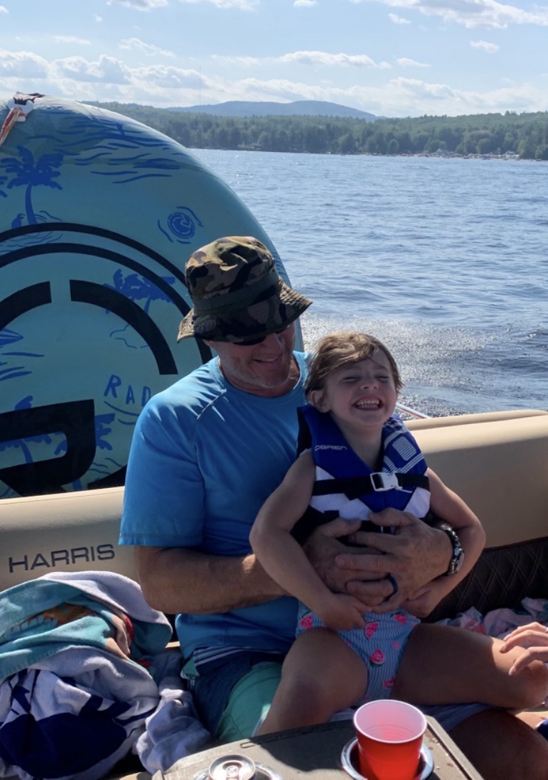 Child wearing a Coast Guard-approved life jacket on a pontoon boat on Sebago Lake