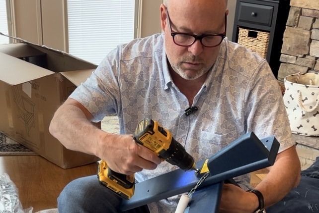 Man using a DeWalt drill to assemble a composite Adirondack chair