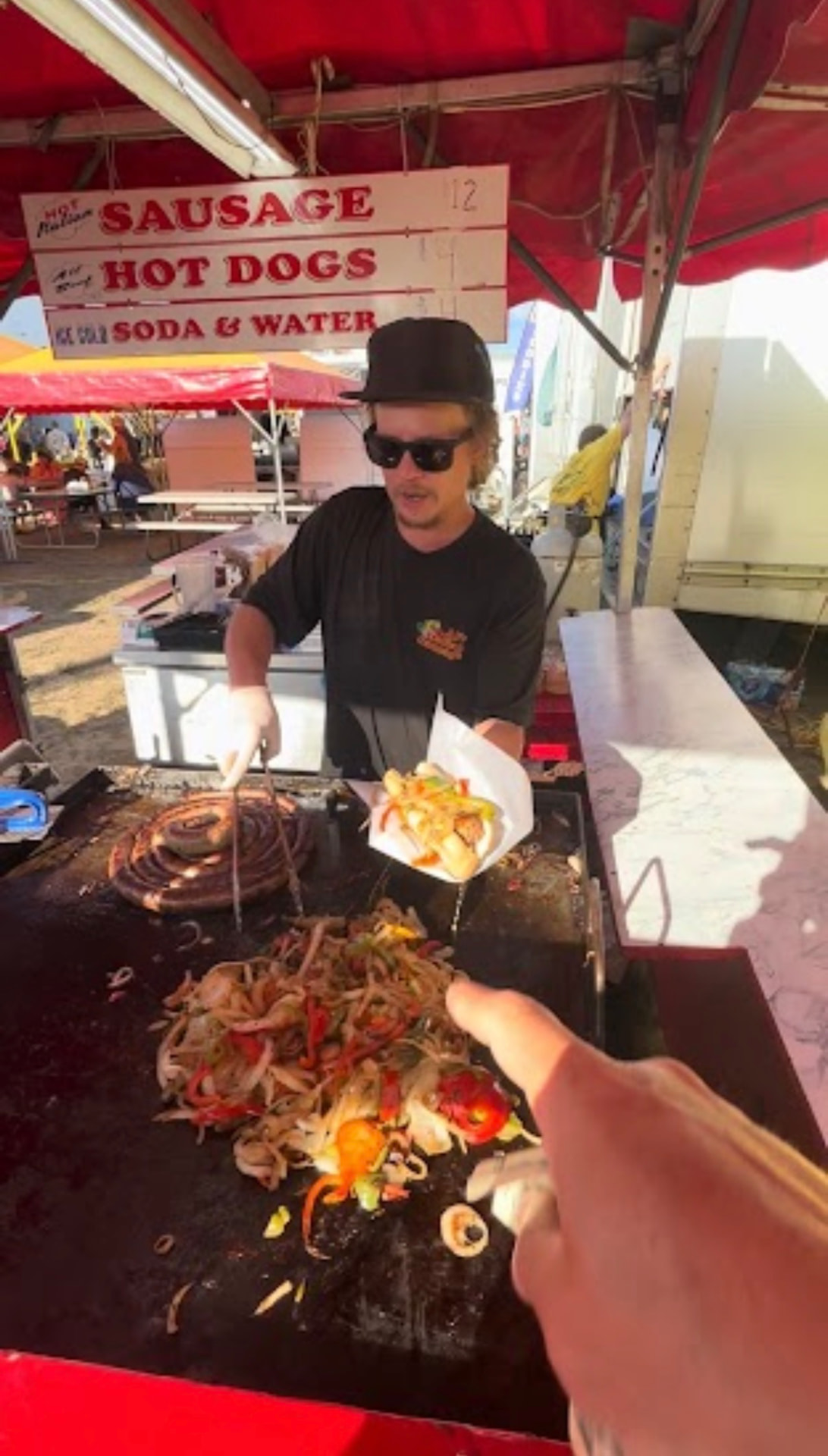 Vendor serving a hot Italian sausage with peppers and onions at the Cumberland County Fair